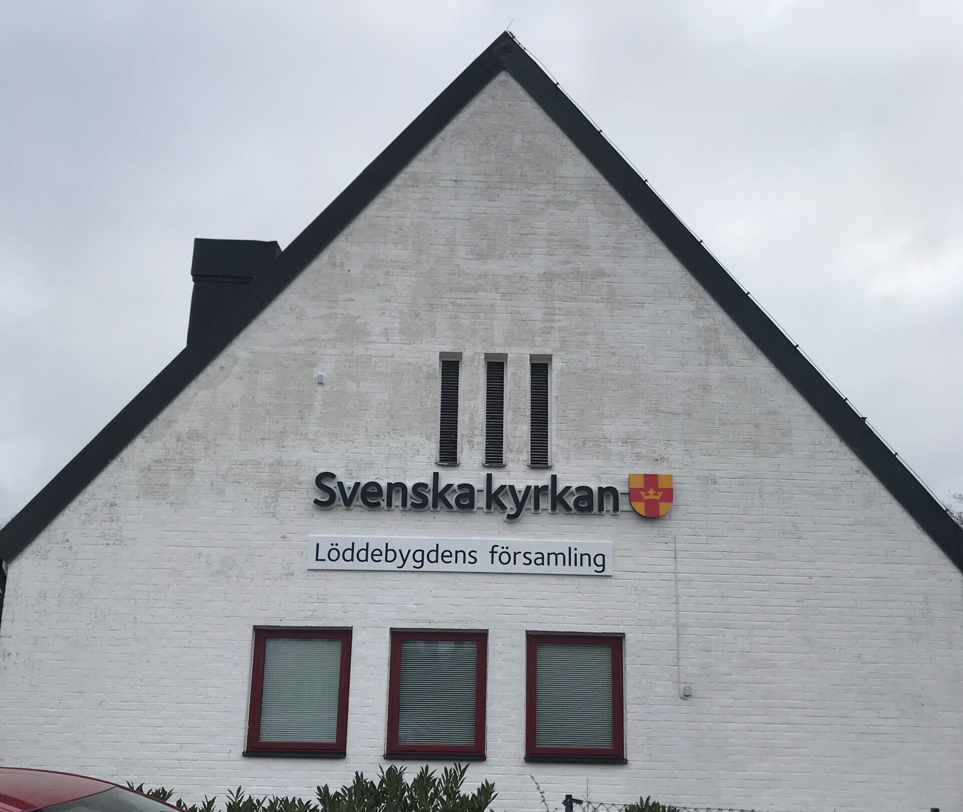 Svenska kyrkan belyst skylt på fasad som lyser både framåt och bakåt med corona effekt