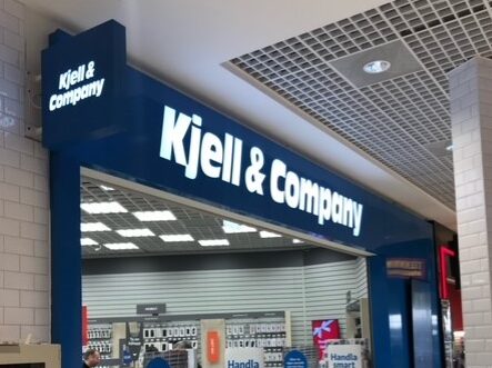 Kjell och company på köpcentrum som en portal till deras butik med utskuren text sk dekaperad samt en flaggskylt